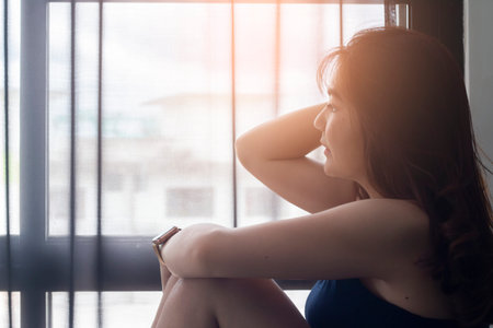 Sad asian women looking thought window in bed roomの写真素材