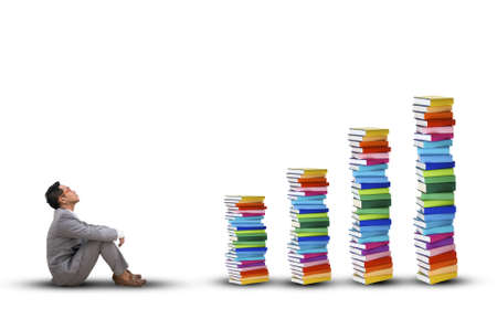 Young business man sitting seeing stack of books . Study goalsの写真素材