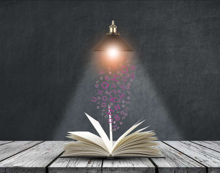 Open book with creative light bulb and falling letters on wood planksの写真素材