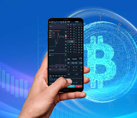 Trading concept. Business hand holding phone and touching screen on smart phone over blur stock chart market backgroundの写真素材