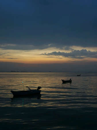 Three boats float on the sea with sunlight of blue hourの素材