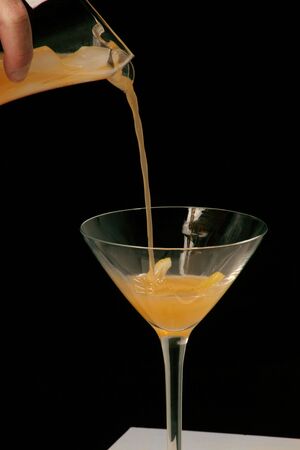 pouring cocktail with a twist of lemon in the glassの写真素材