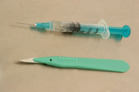 scalpel and syringe on a stainless steel medical trayの写真素材