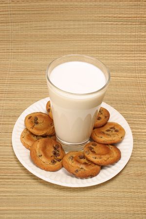 glass of milk surrounded by chocolate chip cookiesの写真素材