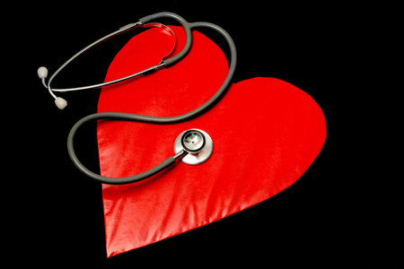 red heart on black background with stethoscope on topの写真素材