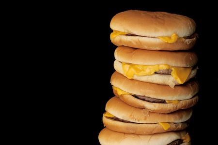 cheeseburgers arranged in a stack with black backgroundの写真素材