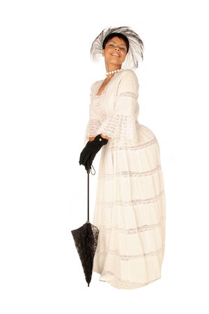 female in lace dress, gloves, hat and standing with a black umbrella in full viewの写真素材
