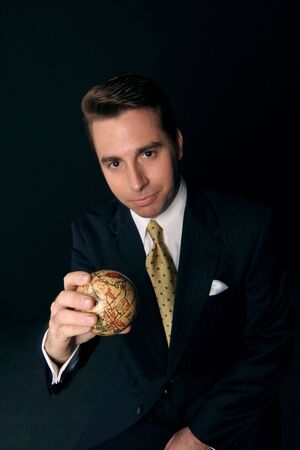 businessman holds the world in his hand on black backdropの写真素材