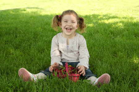 happy young girl sitting on grass in parkの写真素材