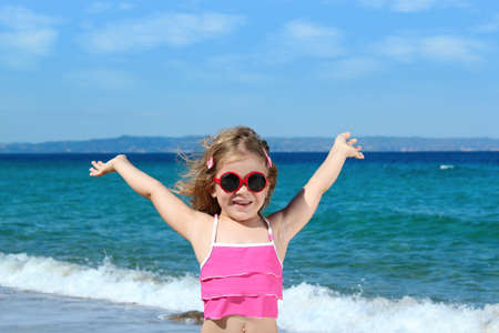 happy little girl with sunglasses on the beachの写真素材