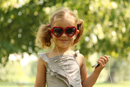 little girl with sunglasses listening musicの写真素材
