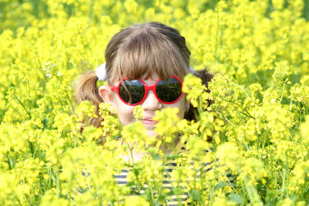 little girl hiding in yellow flowers fieldの写真素材