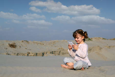 little girl play with tablet pc in desertの写真素材