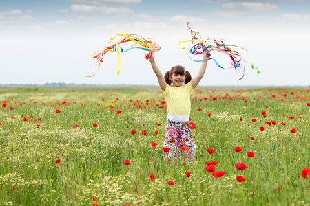 happy little girl with colorful ribbons on meadowの写真素材