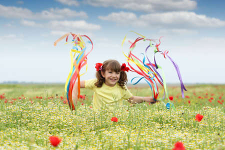 happy little girl with colorful ribbons on fieldの写真素材