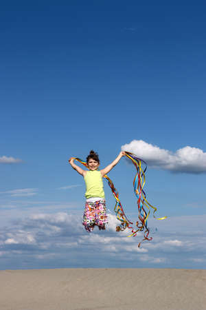 happy little girl playing and jumping on beachの写真素材