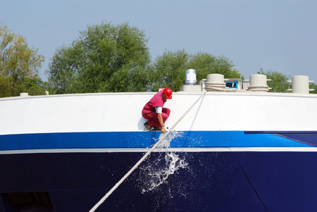 worker smashing a bottle of champagne on the new shipの写真素材