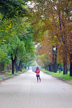 little girl with umbrella on street autumn seasonの写真素材