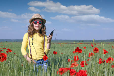 little girl listening music on phone in meadowの写真素材