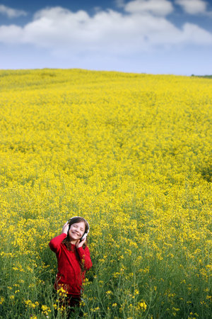 happy little girl listening music on field summer seasonの写真素材