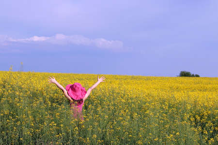 Child with hands up on yellow field summer seasonの写真素材
