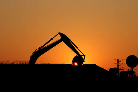 excavator working on construction site silhouetteの写真素材