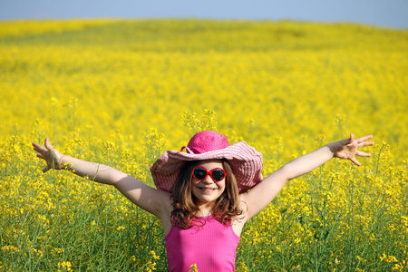 happy little girl with hands up on field spring season