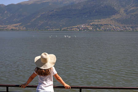The girl watches the swans on the lake Ioannina Greeceの写真素材