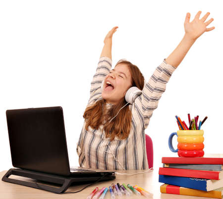Happy little girl with hands up listens to music on laptop の写真素材