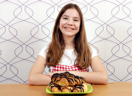 happy little girl with croissants for breakfastの写真素材