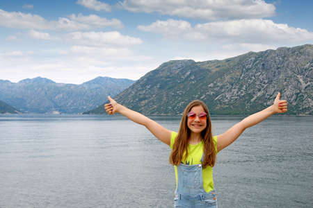 happy teenage girl with thumbs up on summer vacation Kotor bay Montenegroの写真素材