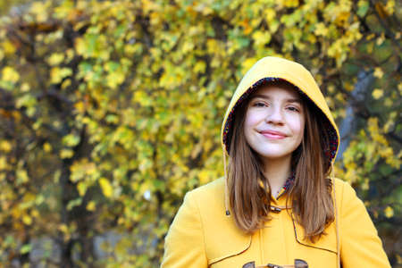 teenage girl in a yellow hooded coat portrait autumn seasonの写真素材