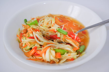 Thai papaya salad (som tum) with a spoon and white plate
