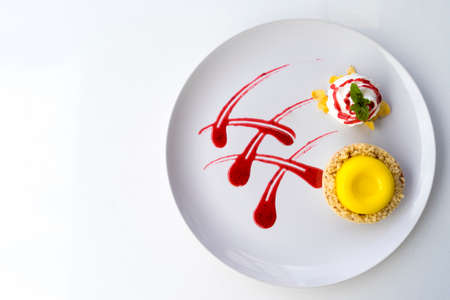 Lemon tart garnished with strawberry sauce. On a white table. Free space for text . Top viewの写真素材