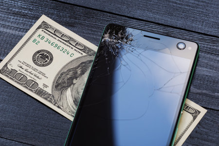 phone with a broken screen, and the money needed for its repairの写真素材