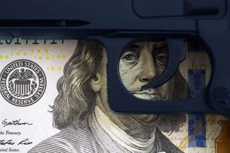 Trigger the gun on the background of the eye drawn on the banknotes. Concept of illegal arms trafficking.の写真素材