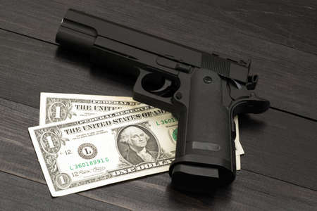 Black gun on banknotes. Concept of armed criminal offensesの写真素材
