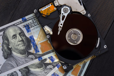 Disassembled hard drive and money on a wooden background. Concept of information safety