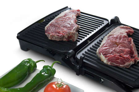 Black electric grill cooking meat with vegetables isolated on whiteの写真素材