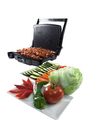 Black electric grill cooking meat and vegetables isolated on whiteの写真素材
