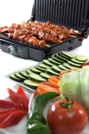 Black electric grill cooking meat and vegetablesの写真素材