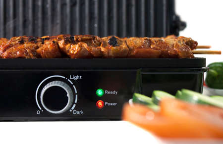 Black electric grill cooking meat and vegetablesの写真素材