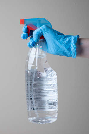 Hand holds a window cleaning bottle with a Blue medical nitrile plastic gloves texturedの写真素材