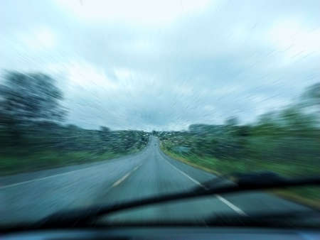 Speed and rain: Rain drops against the glass of the car on a highway with motion blurの写真素材