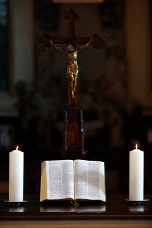 Crucifix, church candles and open bible on an altar. Strasbourg. France.