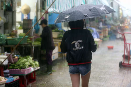 Heavy monsoon rain. woman with umbrella on Saigon Street. Vietnam.の写真素材