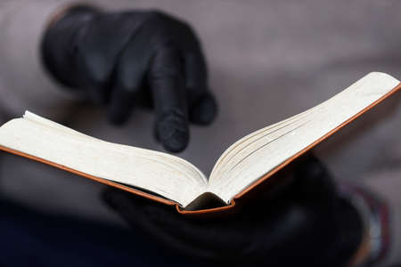 Man reading the bible with protective black disposable gloves.の写真素材