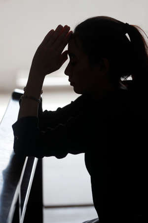 Silhouette of woman praying in a church.の写真素材