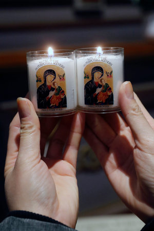 Woman praying in church with candle. Our Lady of Perpetual Help. France.の写真素材