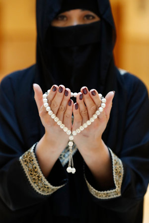 Close up view of a Muslim woman hands in abaya while holding rosary with her hands and praying. Religion praying concept. United Arab Emiratesの写真素材